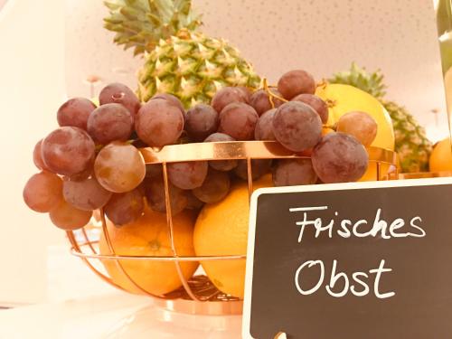 a bowl of fruit with a basket of grapes and pineapple at Hotel Glinde in Hamburg