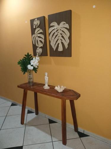 a table with a vase of flowers on a wall at Pousada Dois Rios in Barra do Garças