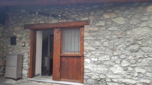 a wooden door on a stone building with a window at La Tour in Gignod