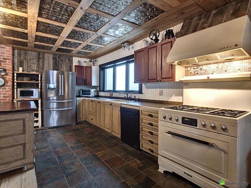 a kitchen with stainless steel appliances and wooden cabinets at Maison du Mont-Mégantic in Lac-Mégantic