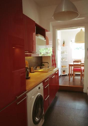 a kitchen with red cabinets and a washer at Lovely Apartment near Belém in Lisbon