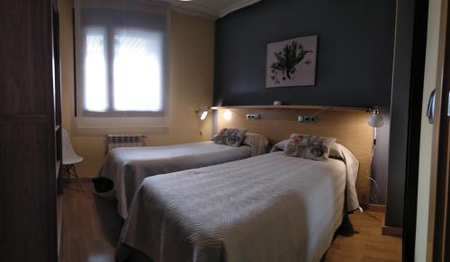 a hotel room with two beds and a window at Apartamento Barqueros, 2 in Salamanca
