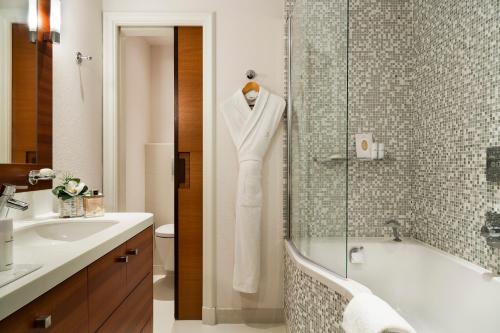 a bathroom with a robe hanging on a shower door at Hôtel Barrière Le Normandy in Deauville