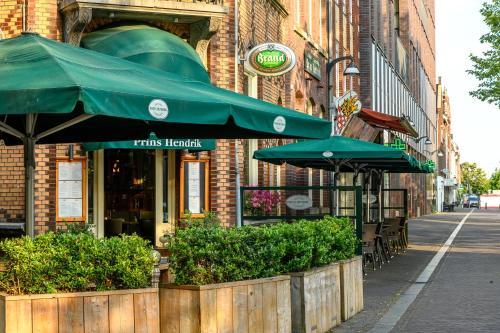 a restaurant with green umbrellas in front of a building at BnB prins Hendrik Venlo in Venlo