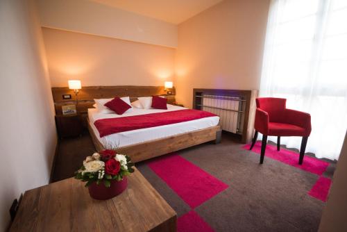 a hotel room with a bed and a red chair at Hotel Lavina in Jahorina