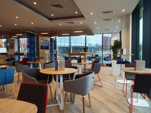 a restaurant with tables and chairs and windows at Holiday Inn Express - Stockport by IHG in Stockport