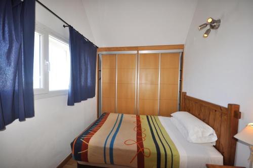 a bedroom with a bed with blue curtains and a window at Apartamentos Sabica in Sierra Nevada