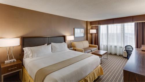 a hotel room with a large bed and a chair at Holiday Inn Express Washington DC SW - Springfield by IHG in Springfield