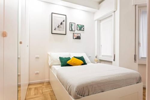 a white bedroom with a bed with yellow and green pillows at Easylife - Milano - D'Annunzio - Navigli in Milan