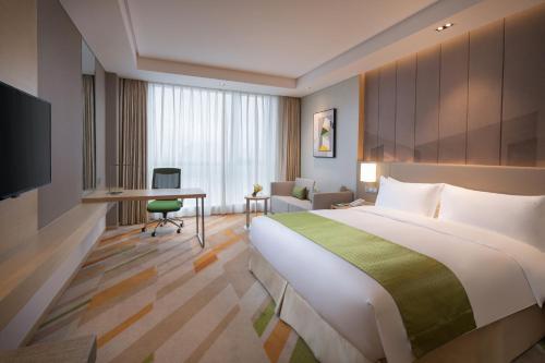 a hotel room with a large bed and a desk at Holiday Inn Wuxi Taihu New City by IHG in Wuxi