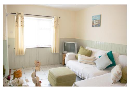 uma sala de estar com um sofá branco e uma TV em no 3 Leitrim Road em Carrick on Shannon