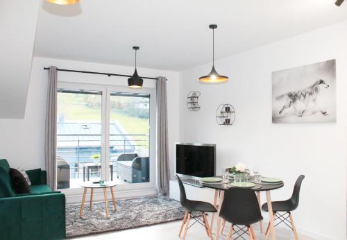 een woonkamer met een tafel en een groene bank bij Apartamenty Ski & Fun Spokojna in Wisła