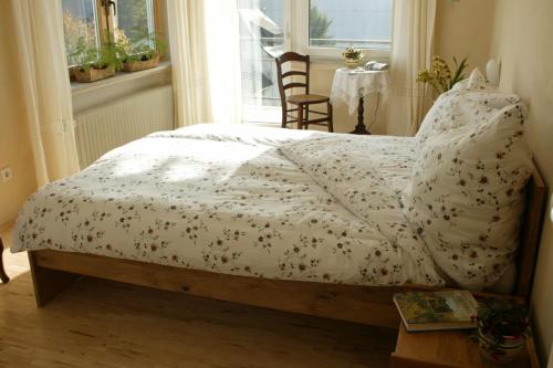 ein Schlafzimmer mit einem Bett mit einer weißen Bettdecke und einem Fenster in der Unterkunft Landhotel Pension Haus Sonneck in Manderscheid