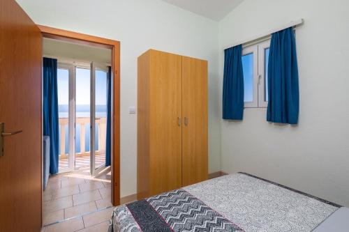 a bedroom with a bed and blue curtains at Apartments & Restaurant Galeb in Marusici 