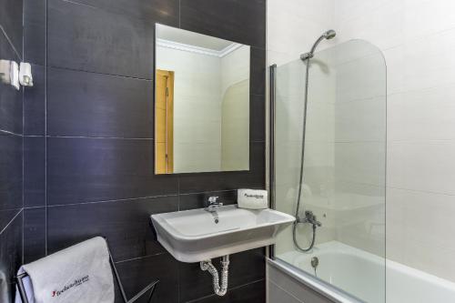 ein Badezimmer mit einem Waschbecken, einem Spiegel und einer Badewanne in der Unterkunft FLH Vila Real Santo António Flat with Pool in Vila Real de Santo António
