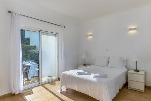 um quarto com uma cama branca e uma grande janela em FLH Praia da Luz Apartment with Pool em Alagoas