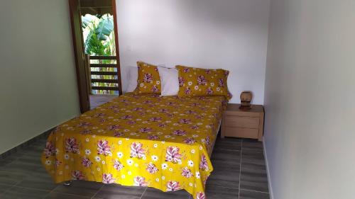 una camera da letto con un letto e un piumone giallo di APPARTEMENT MILO 1 a Bouillante