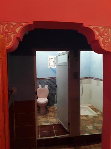 uma casa de banho com um WC e uma parede vermelha em Auberge Restaurant Les Coquelicots em Aït Tamellil