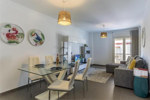 a dining room and living room with a glass table and chairs at FLH Vila Real Santo António Flat with Pool in Vila Real de Santo António