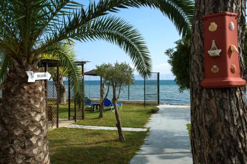 a park with palm trees and a playground and the ocean at Sand and Sea in Kavos