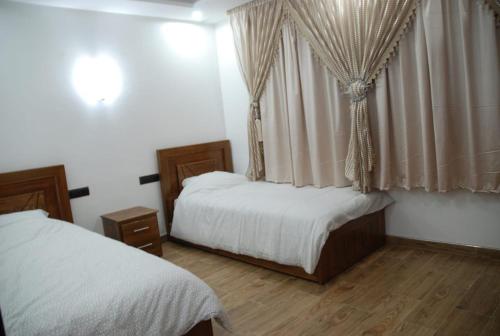 a bedroom with two beds and a window with curtains at Elmoapart in Agadir