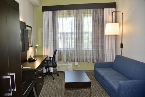 a hotel room with a blue couch and a desk and a computer at Holiday Inn Express Windsor Sonoma Wine Country, an IHG Hotel in Windsor