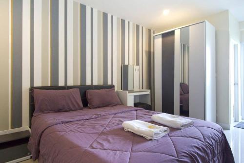 una camera da letto con un letto viola e due asciugamani di The Arni Sukhumvit 101 a Bangkok