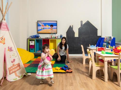 a young girl holding a teddy bear in a play room at Vinhedo Plaza Hotel in Vinhedo