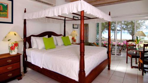 Oualie Beach Resort في نيفيس: غرفة نوم بسرير مظلة مع طاولة وكراسي