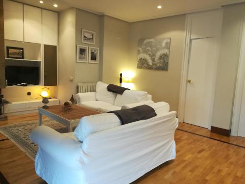 una sala de estar con 2 sofás blancos y una mesa. en LARRAITZ en San Sebastián