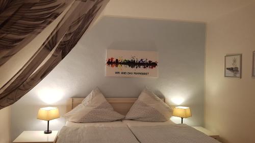Ferien-& Monteurwohnung Koenen2 nah am Westfield Centro في أوبرهاوزن: غرفة نوم بسرير مع مصباحين وصورة على الحائط