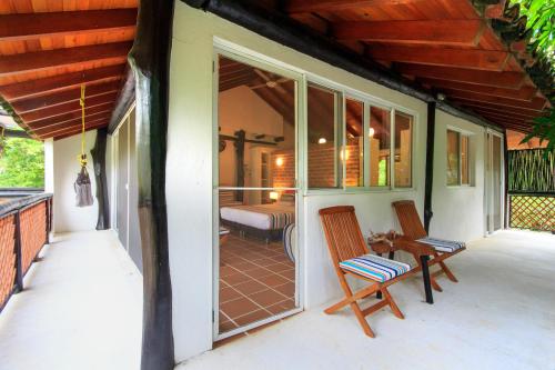 a porch with two chairs and a bed at La Mar de Bien in Buritaca