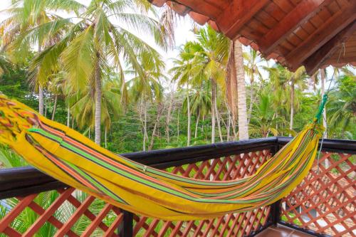 a yellow hammock on a porch with palm trees at La Mar de Bien in Buritaca