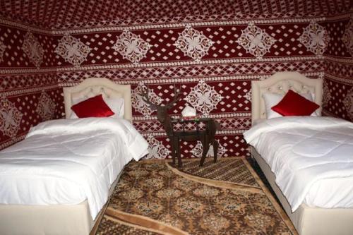 two beds in a room with red and white wallpaper at WadiRum Mobile Camp in Wadi Rum