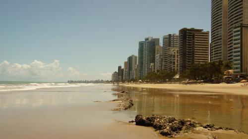 uma praia de areia com edifícios altos e o oceano em The Place Hostel no Recife
