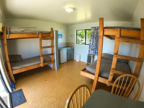 a room with two bunk beds and a table and chairs at Marahau Beach Camp in Marahau