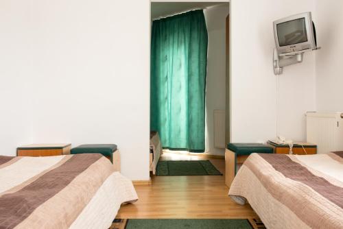 a room with two beds and a tv on the wall at Hotel Beta in Cluj-Napoca