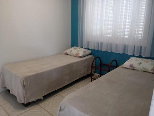 two beds in a room with a window at Casa 2 quartos - São Bernardo in São Francisco de Paula
