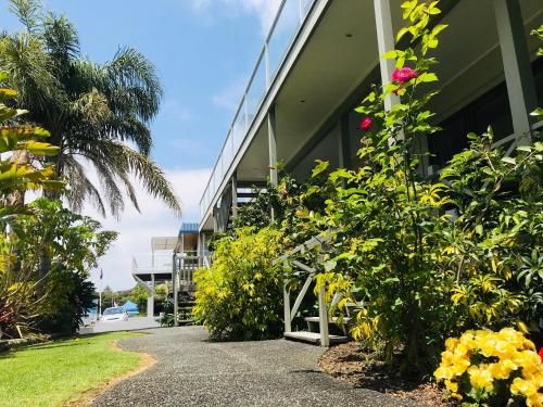 a walkway in front of a building with flowers at Bounty Motel in Paihia