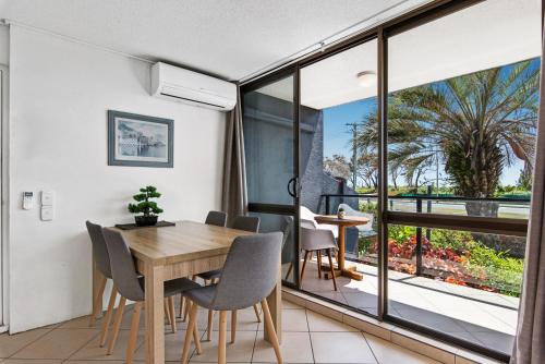 a dining room with a table and chairs and a balcony at Mylos Holiday Apartments in Alexandra Headland