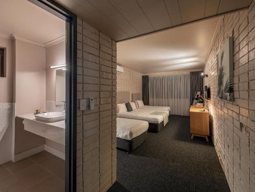 Habitación de hotel con 2 camas y lavamanos en Palms Hotel en Sídney