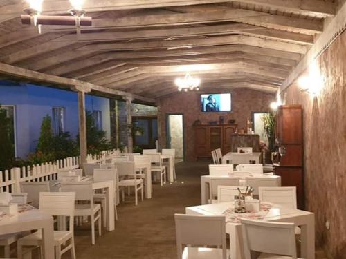 uma sala de jantar com mesas brancas e cadeiras brancas em Pensiunea Oana ☆☆☆ em Şoimuş