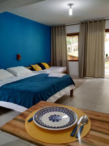 Un dormitorio con 2 camas y una mesa con un plato. en Vila Hen Praia do Forte - Studios com Varanda e Piscina - Quintas do Castelo da Torre - Reserva Sapiranga - 3,6km da Vila en Praia do Forte