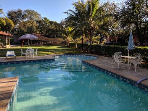 a swimming pool with chairs and a table at Pousada Canto do Rio in Três Marias