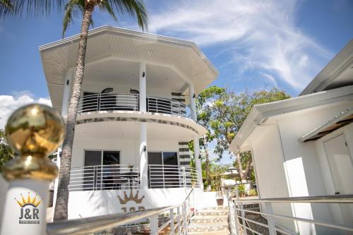 a white house with a balcony and a palm tree at J&R Residence in Anda