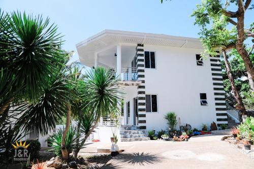 a white building with palm trees in front of it at J&R Residence in Anda