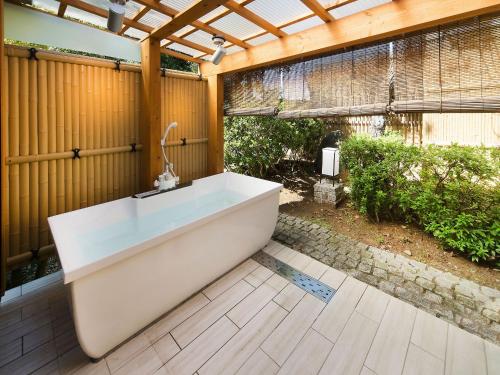 a bath tub sitting on a wooden floor in a bathroom at Yuraku Hotel in Awara