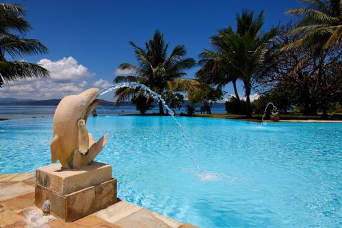 a dolphin statue in the water next to a pool at Gangga Island Resort & Spa in Serai