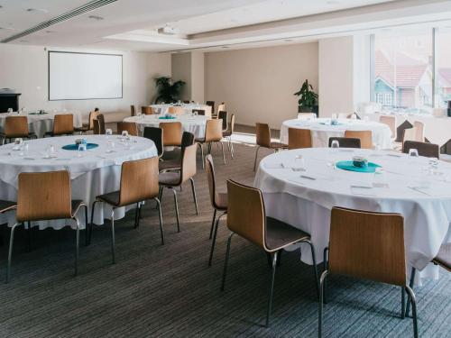 a conference room with tables and chairs and a whiteboard at Novotel Newcastle Beach in Newcastle