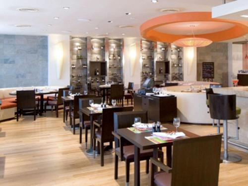 a restaurant with tables and chairs and a bar at Novotel Mumbai Juhu Beach in Mumbai